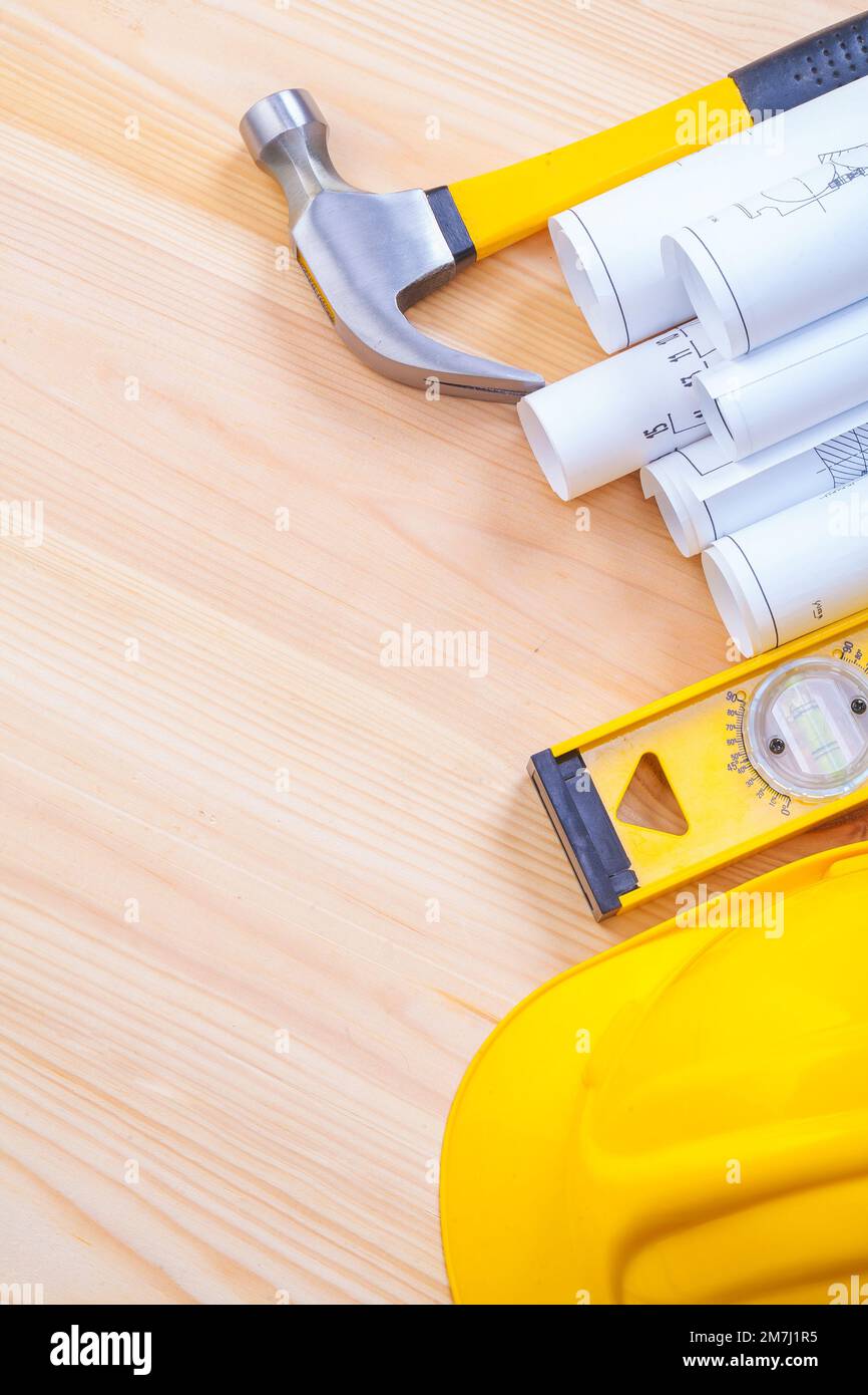 white blueprints claw hammer construction level yeelow helmet on wooden