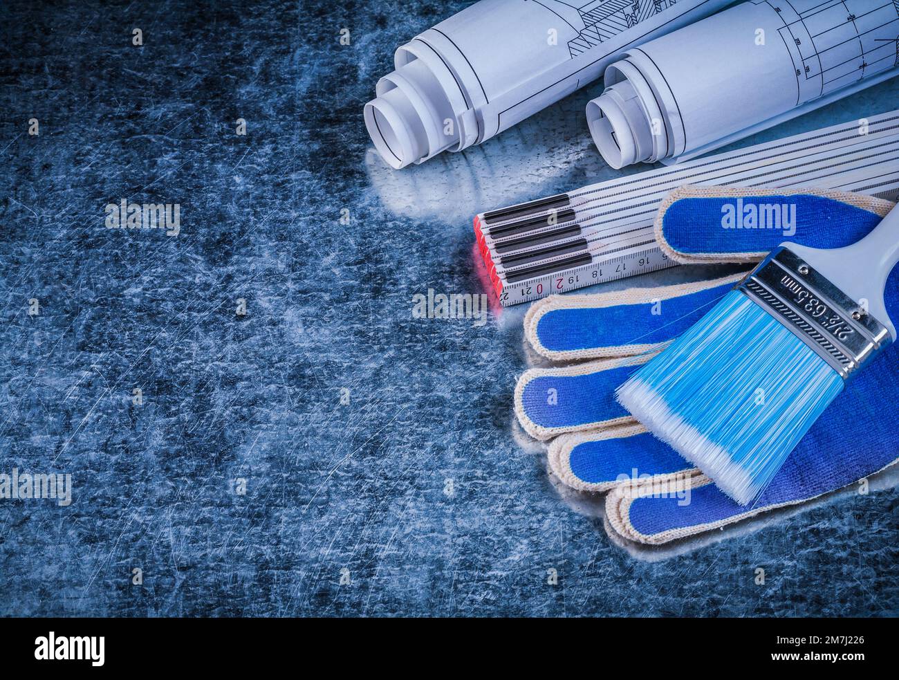 Wooden meter paintbrushes protective gloves and rolled blueprints ...