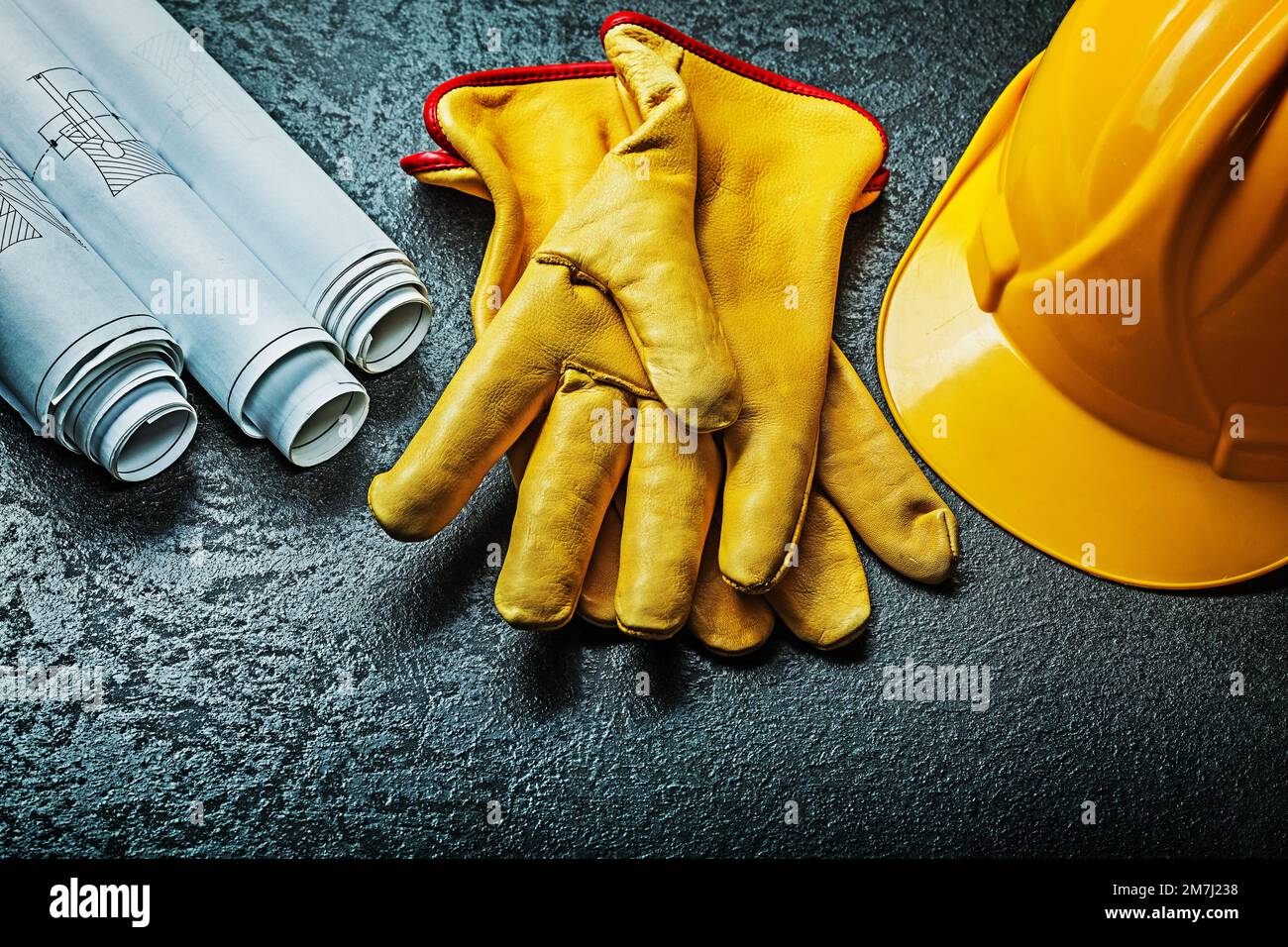 working gloves with yellow helmet and rolled blueprints Stock Photo - Alamy