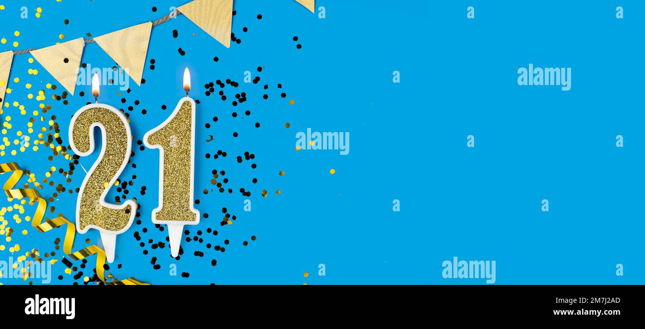 Number 21 gold celebration candle on star and glitter blue background. Copy space. Stock Photo