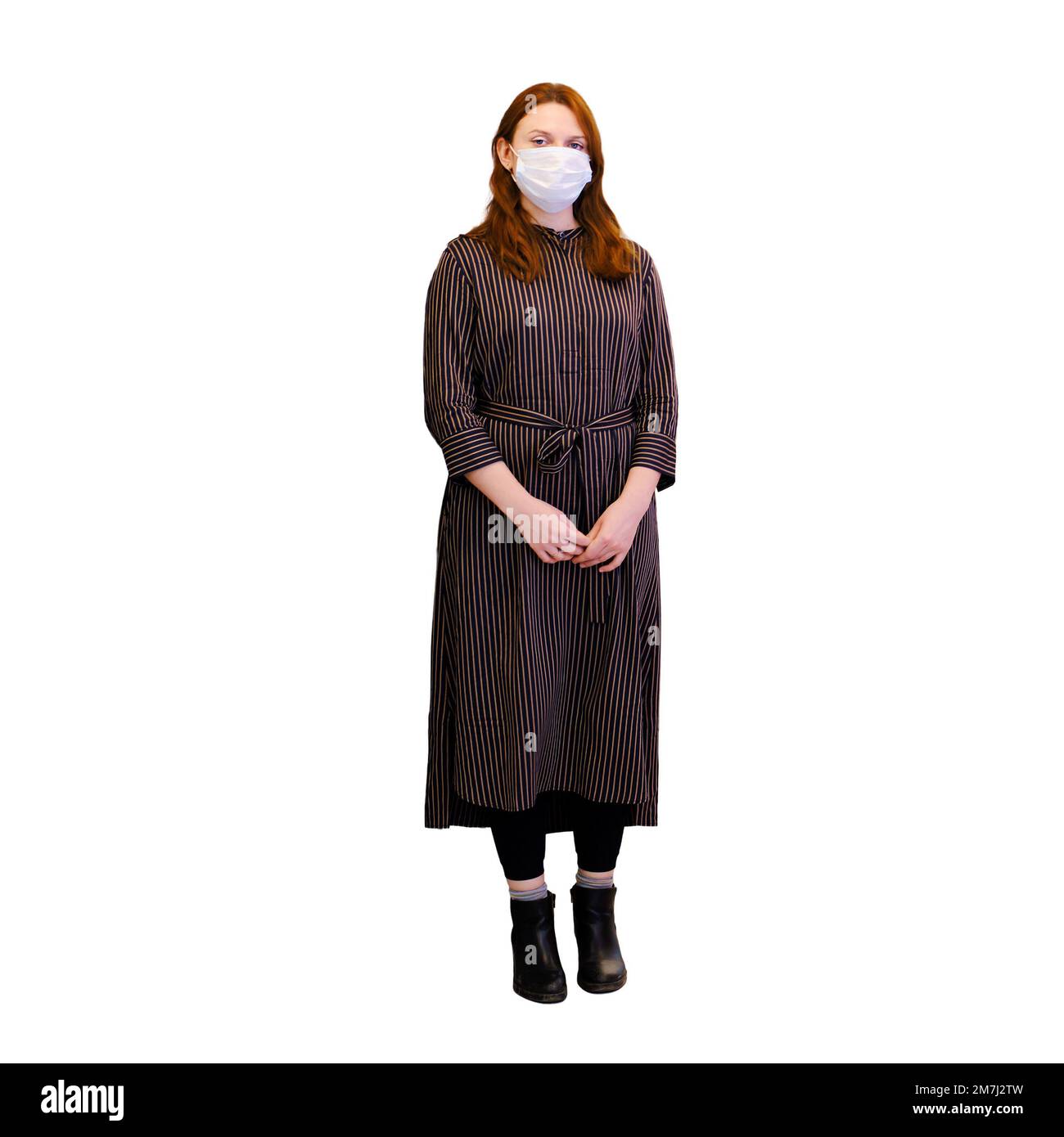 A sad woman in a medical mask stands in an empty hospital corridor ...