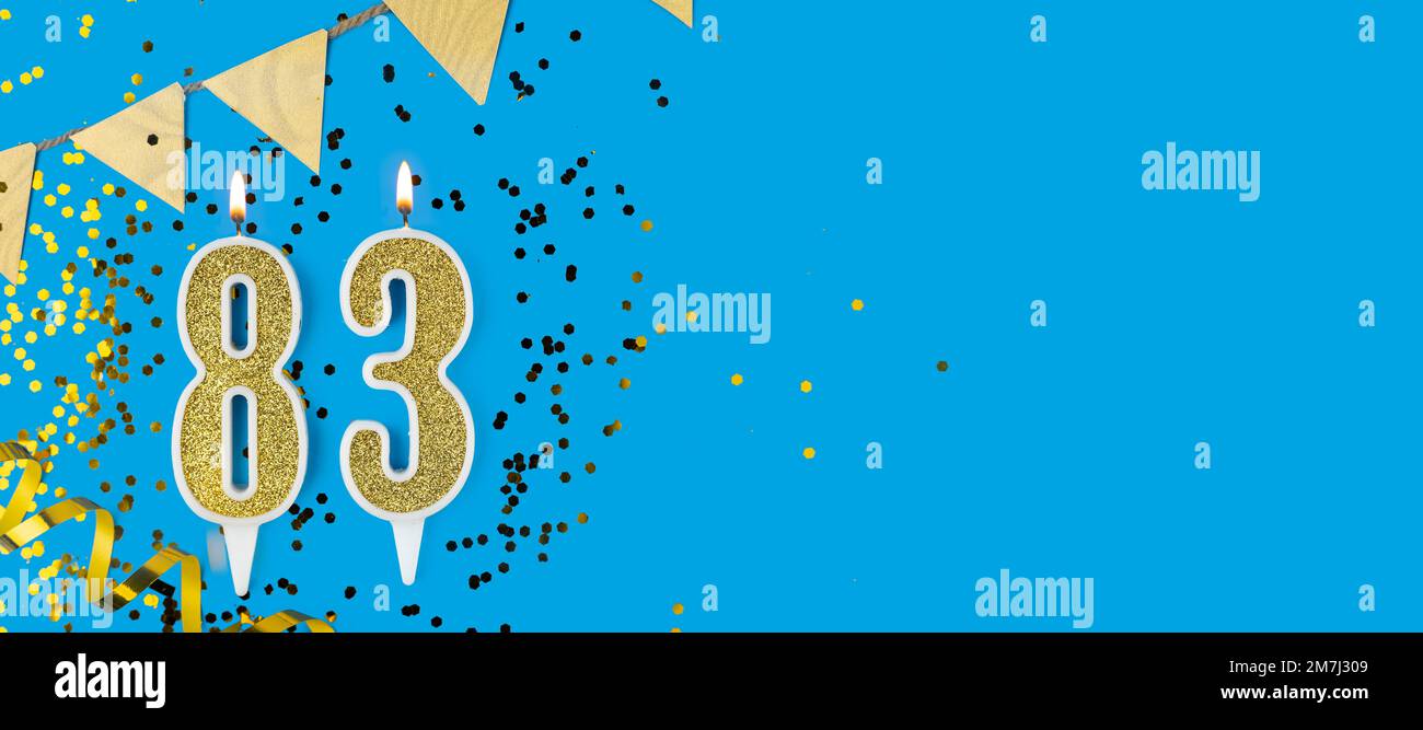 Golden candle number eighty three. Birthday or anniversary card with the inscription 83 on blue background. Anniversary celebration. Banner. Stock Photo