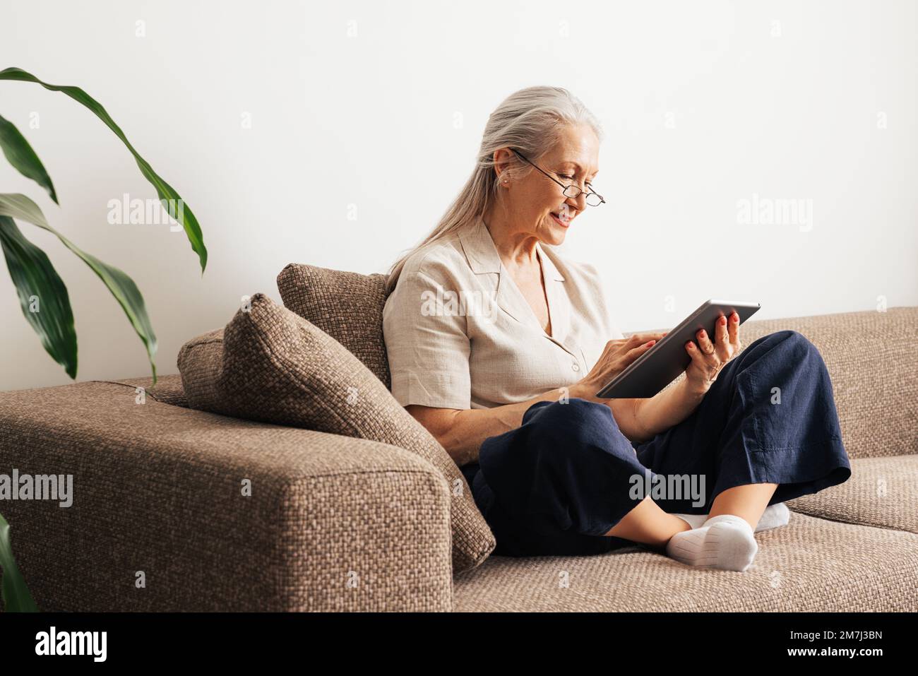 Woman sitting on gray couch hi-res stock photography and images - Alamy