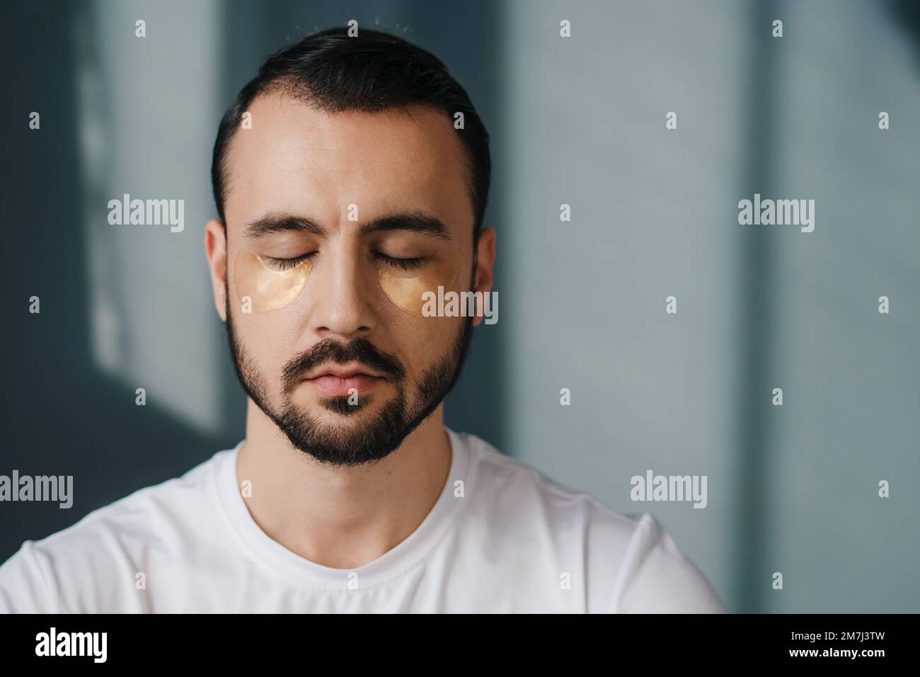 Relaxed handsome man sitting with his eyes closed and meditating while