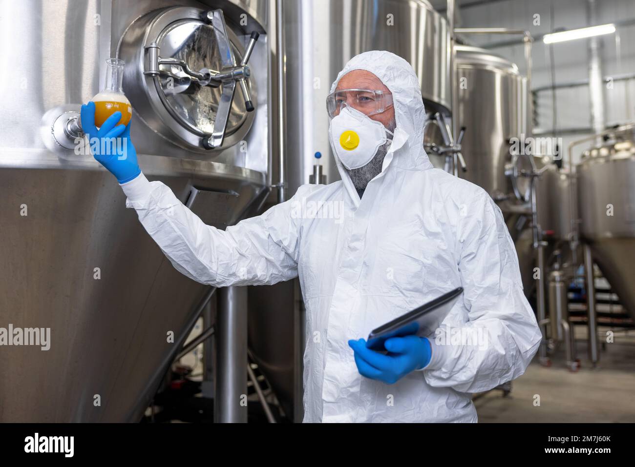 Brewery technologist with a sample of beverage in a vessel Stock Photo