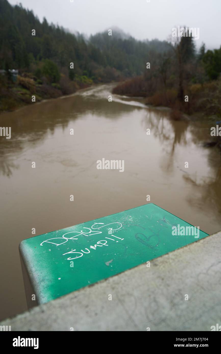 Russian River view from the brdige in Forestville, California, on a stormy December day. Graffiti on bridge says Jump Days. Stock Photo
