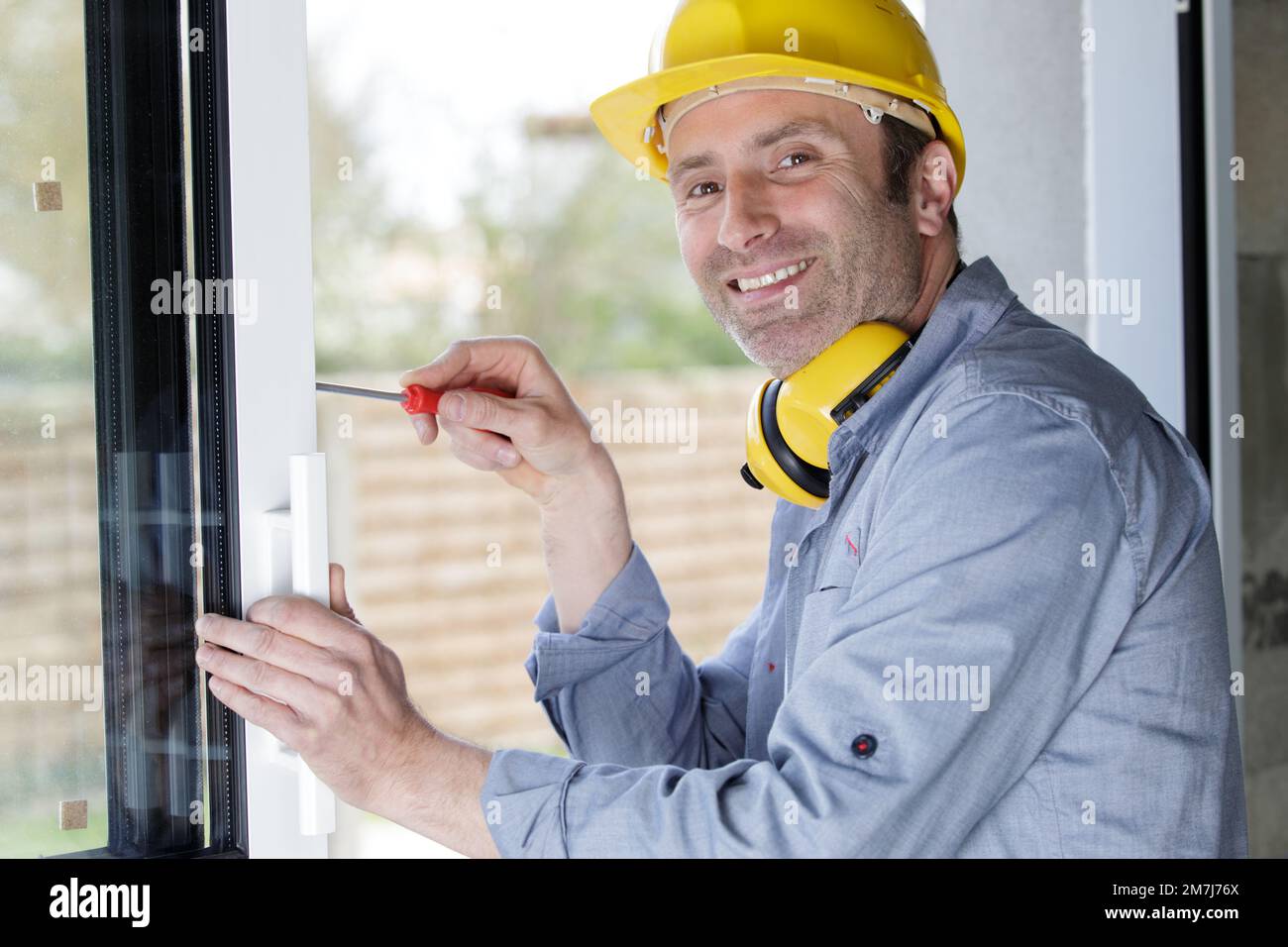 happy man drilling a window frame Stock Photo