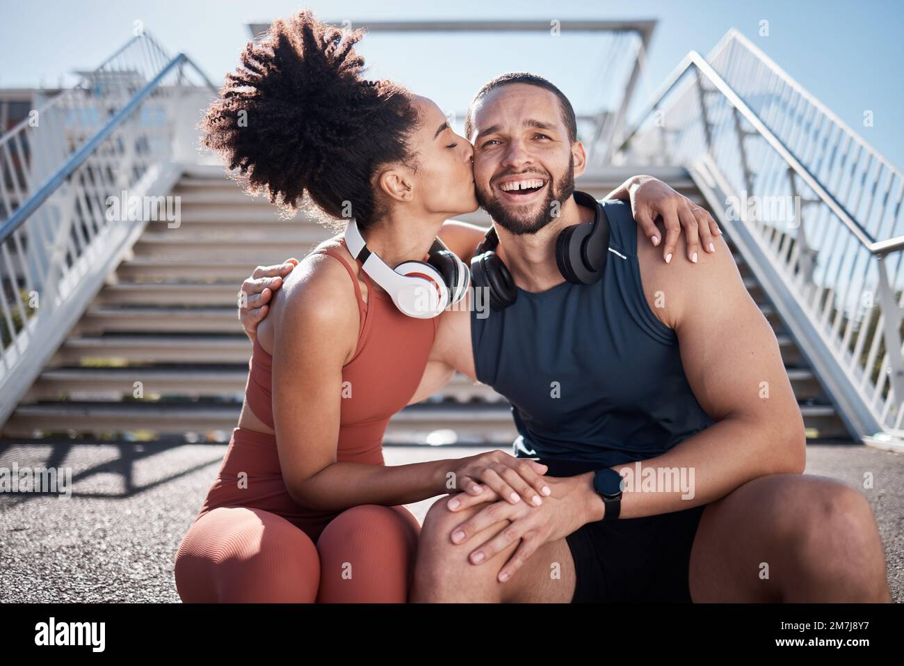 Sports, love and woman kissing man on stairs in city on break from exercise workout. Motivation, health and fitness goals, couple rest and kiss with Stock Photo