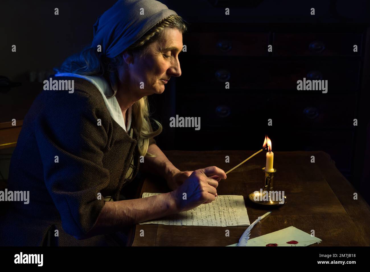 Lady in authentic medieval costume is lighting a candle Stock Photo Alamy