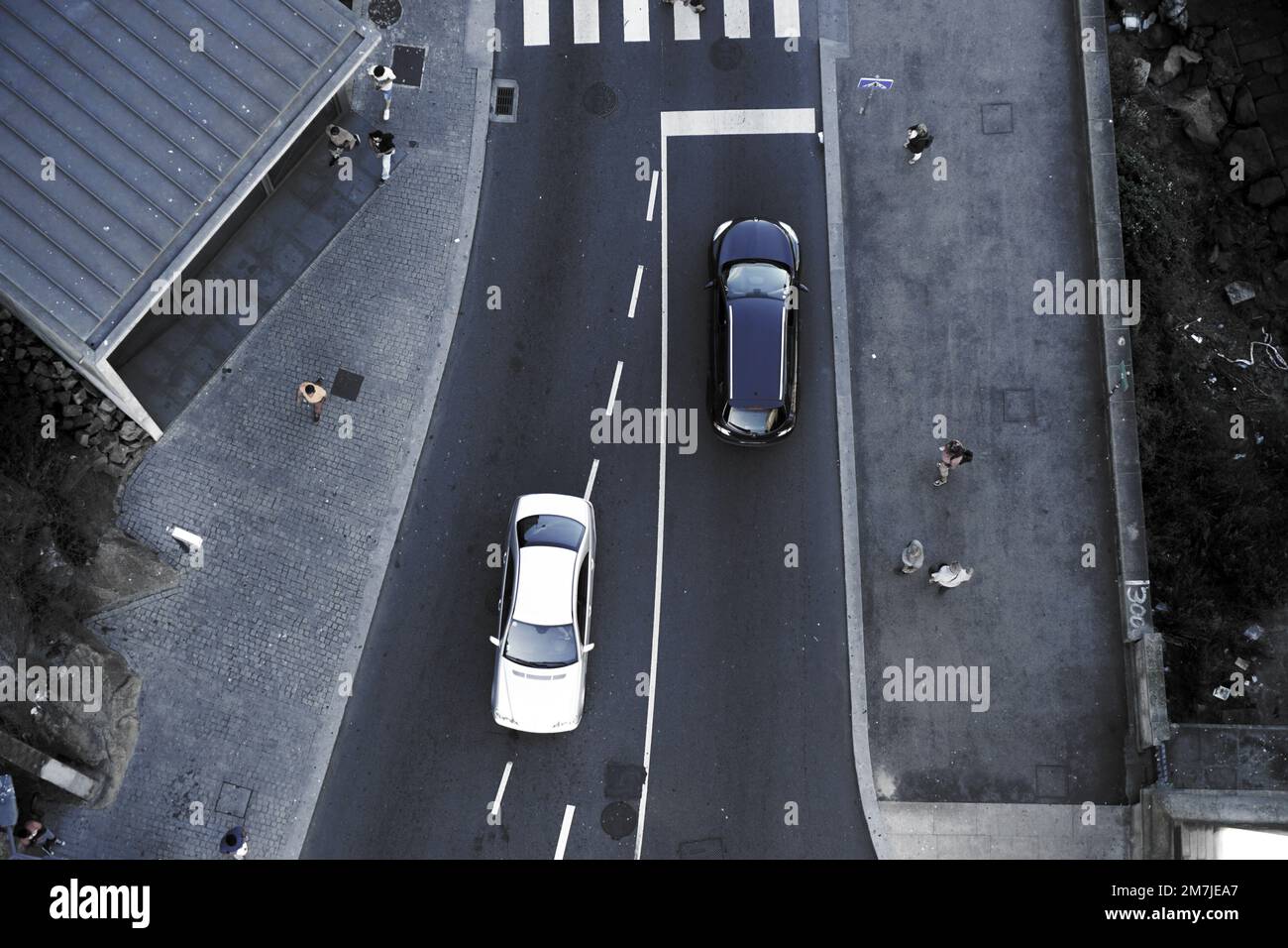 An aerial top view of white and black cars driving in opposite