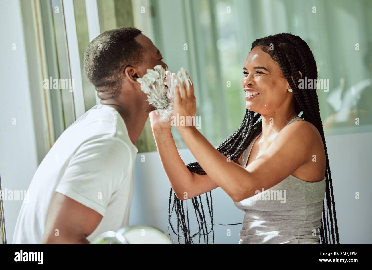 Shave, playing and funny with a black couple laughing or joking together in the bathroom of their home. Love, shaving and laughter with a man and Stock Photo