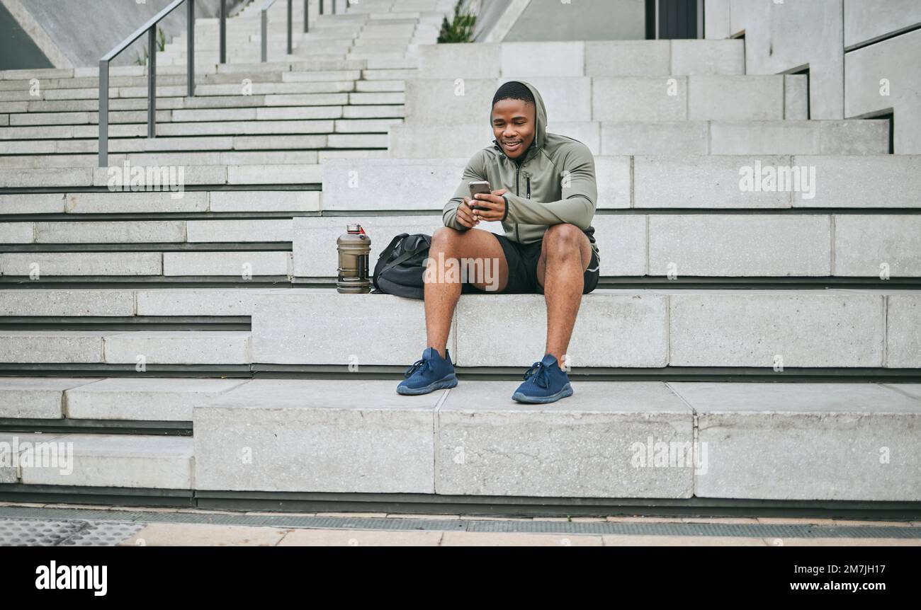 Social media, phone or black man on steps after fitness training, exercise or workout with a sports bag in Miami, Florida. Social networking, happy or Stock Photo