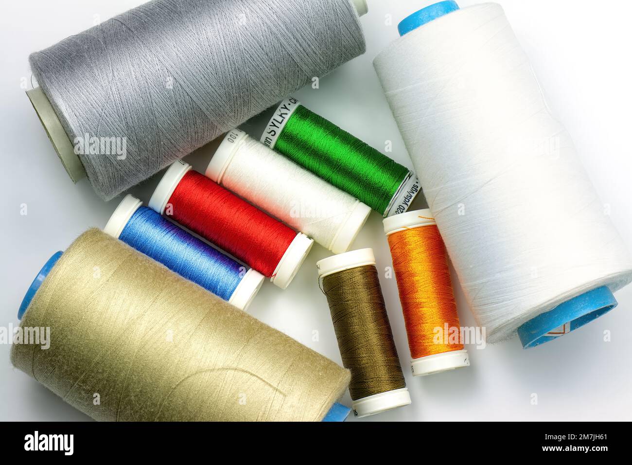 Multicolored sewing threads. Background of spools with colorful sewing threads, top view. Stock Photo