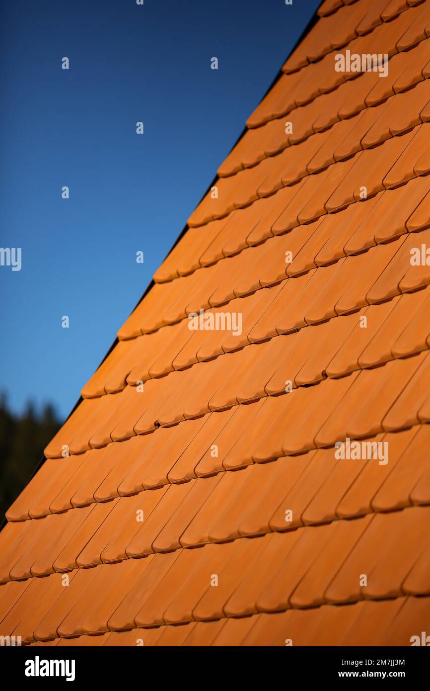 Details of orange brick tile roof patterns with clear bright blue sky in the background. Close-up of House Architecture patterns. Stock Photo