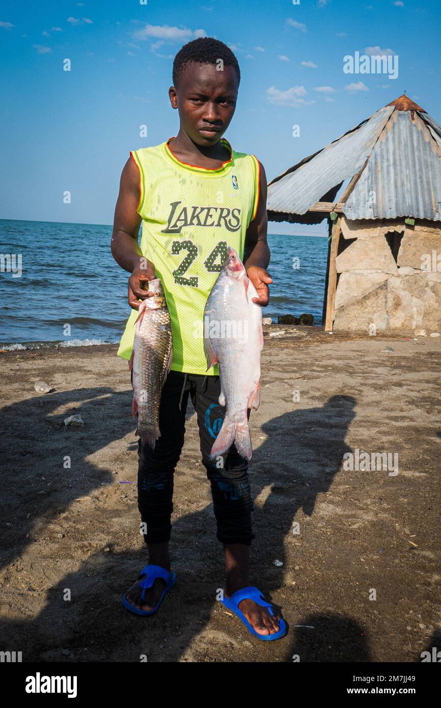 An El Molo tribe fisherman holding a fish at El Molo Vilage in Lake Turkana, Kenya Stock Photo