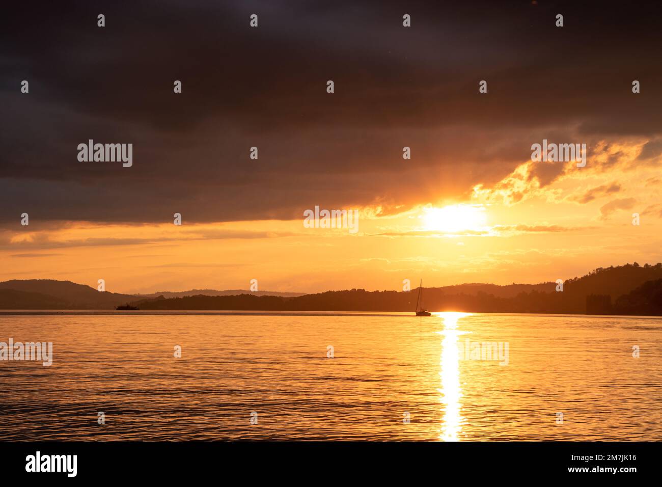 A sailboat on a lake with sunset Stock Photo - Alamy