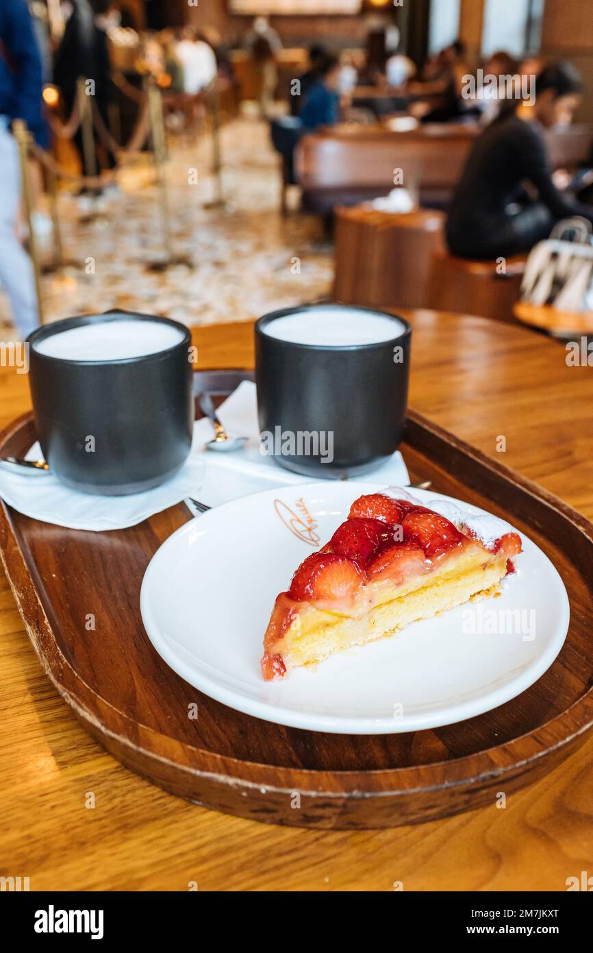 Strawberry Tart and Two Cappuccino Coffee Starbuck Mugs Served on a Tray in Starbucks Reserve Roastery Shop, Milan Italy Stock Photo