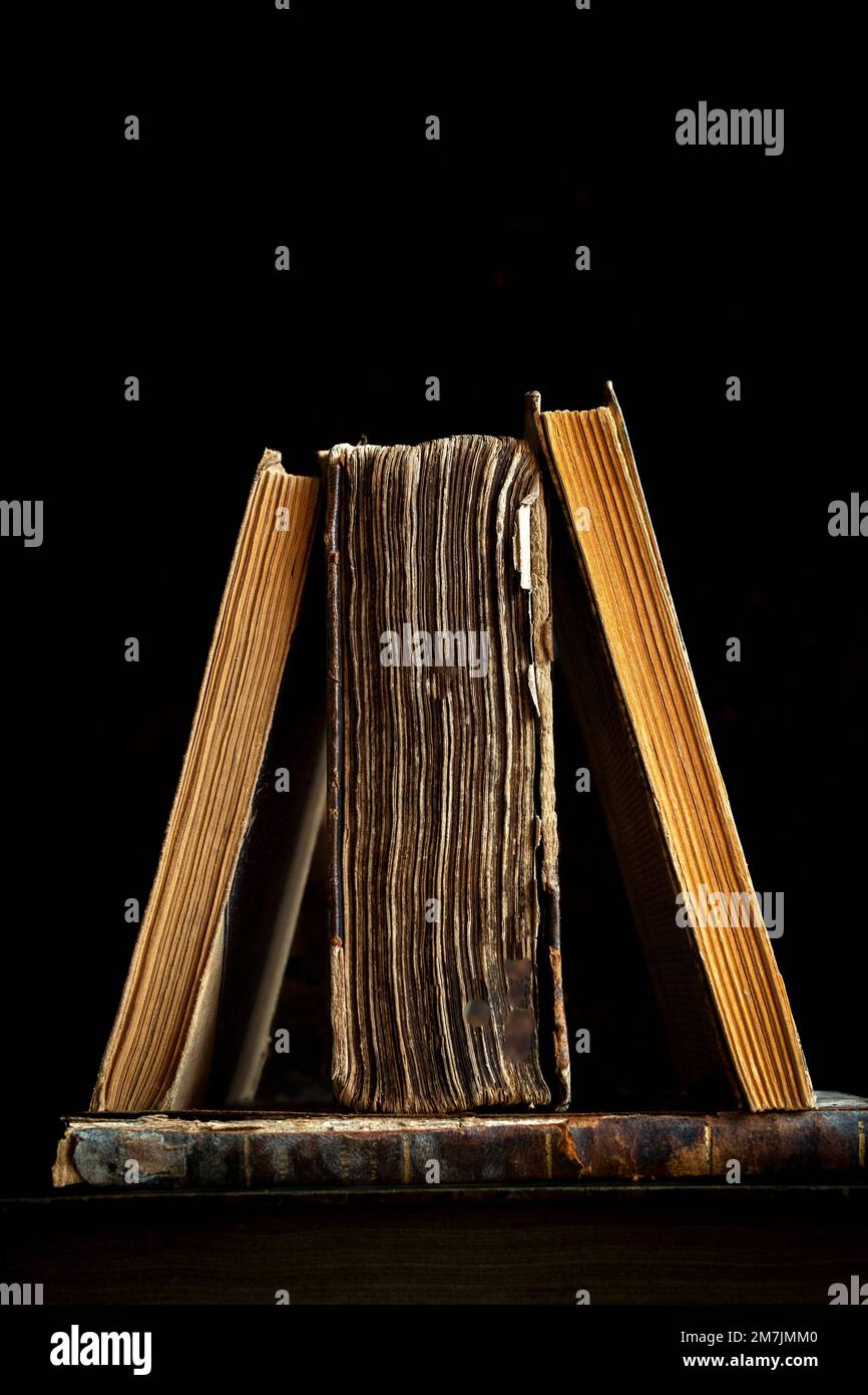 Vertical closeup of three old books on a black background Stock Photo