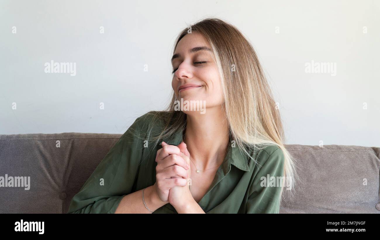 Peaceful woman smiling and blessing at home. International women's day concept for March 8. Young blonde woman portrait. Stock Photo