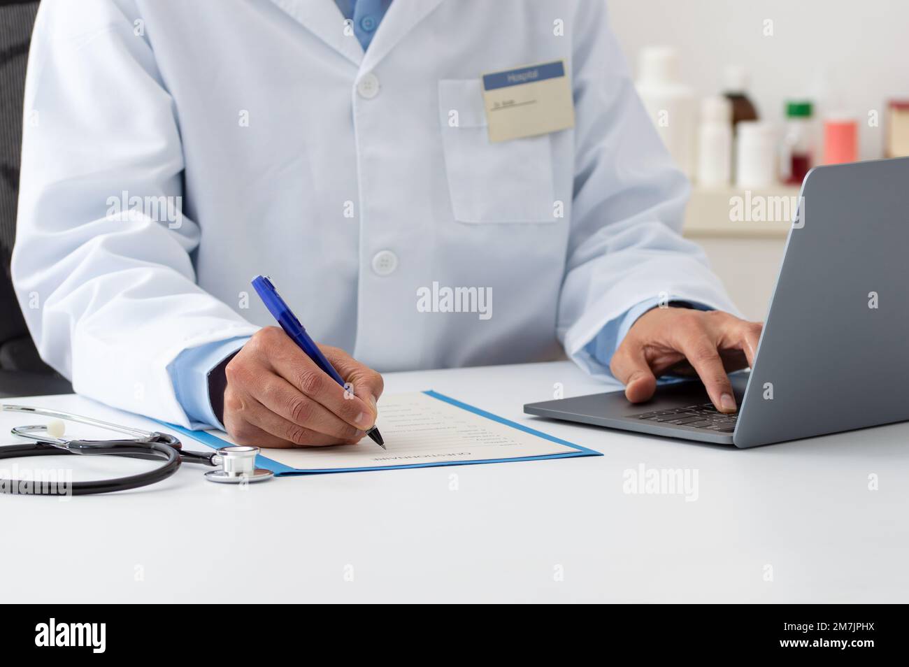 Closeup shot of a doctor using a computer and making notes in an office at hospital Stock Photo