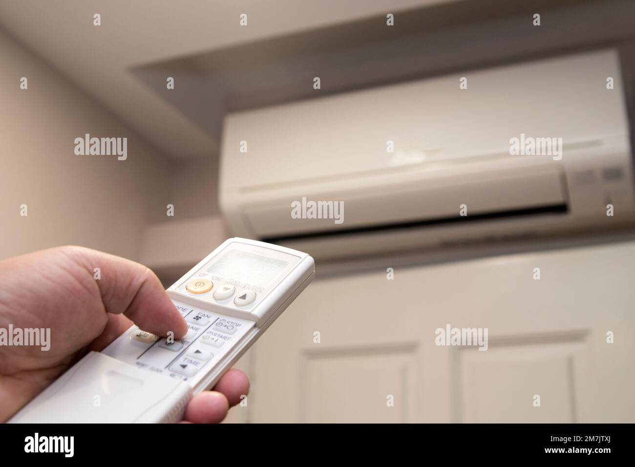 Air conditioner with left aligned hand operating the remote control ...