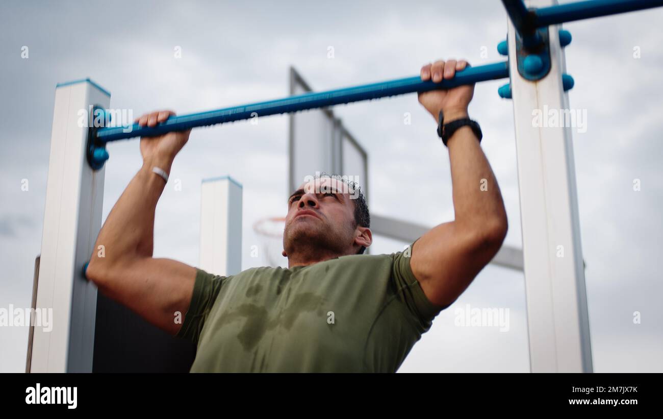 Man is doing pull ups exercises on horizontal bar Stock Photo