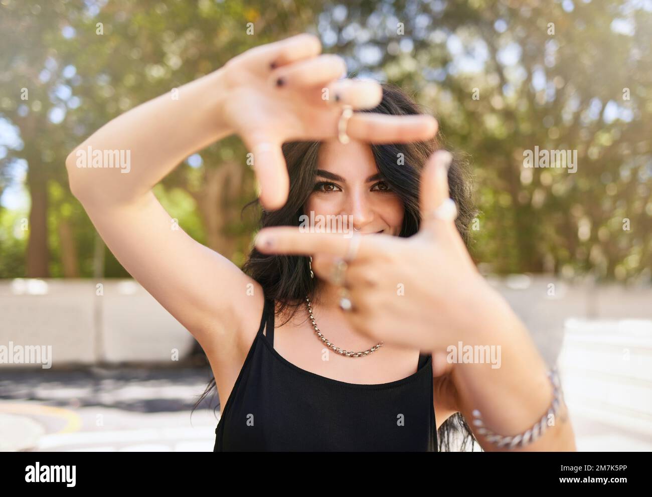 Creative girl and portrait with hand frame for inspiration, idea and happiness in sunshine at park. Youth, trendy and edgy emo gen z woman with Stock Photo