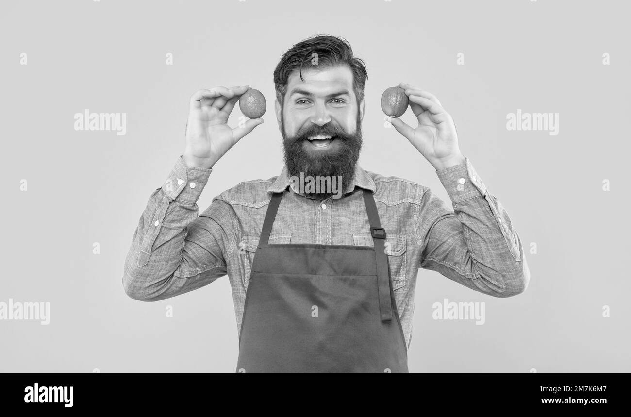 Happy man in red apron holding fresh limes citrus fruits yellow