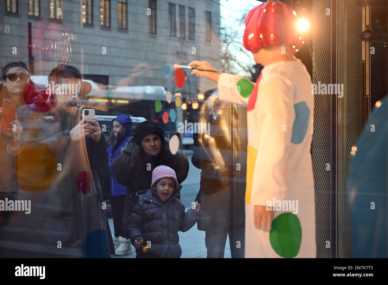 A young child reacts looking at a realistic looking Yayoi Kusama