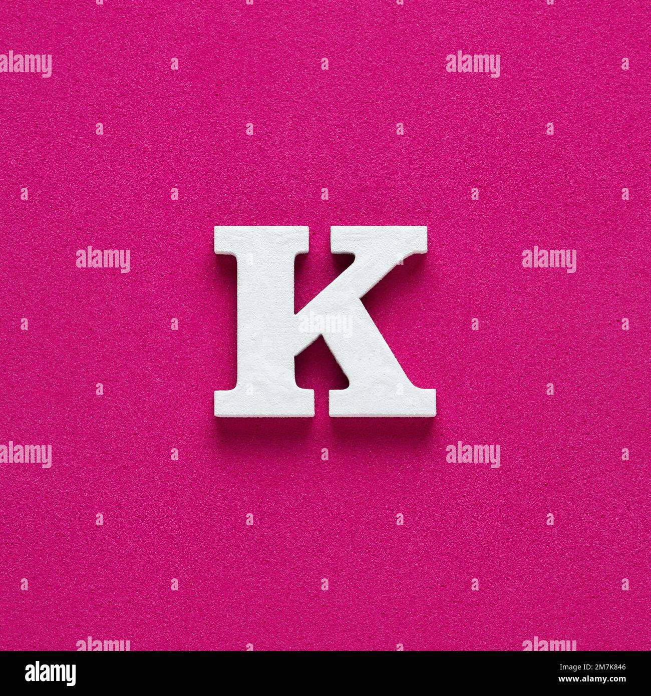 Alphabet letter K White wooden letter on rhodamine red background