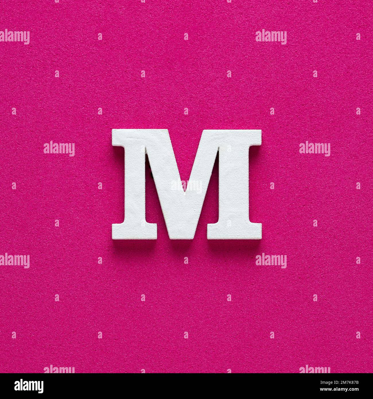Alphabet letter M - White wooden letter on rhodamine red background