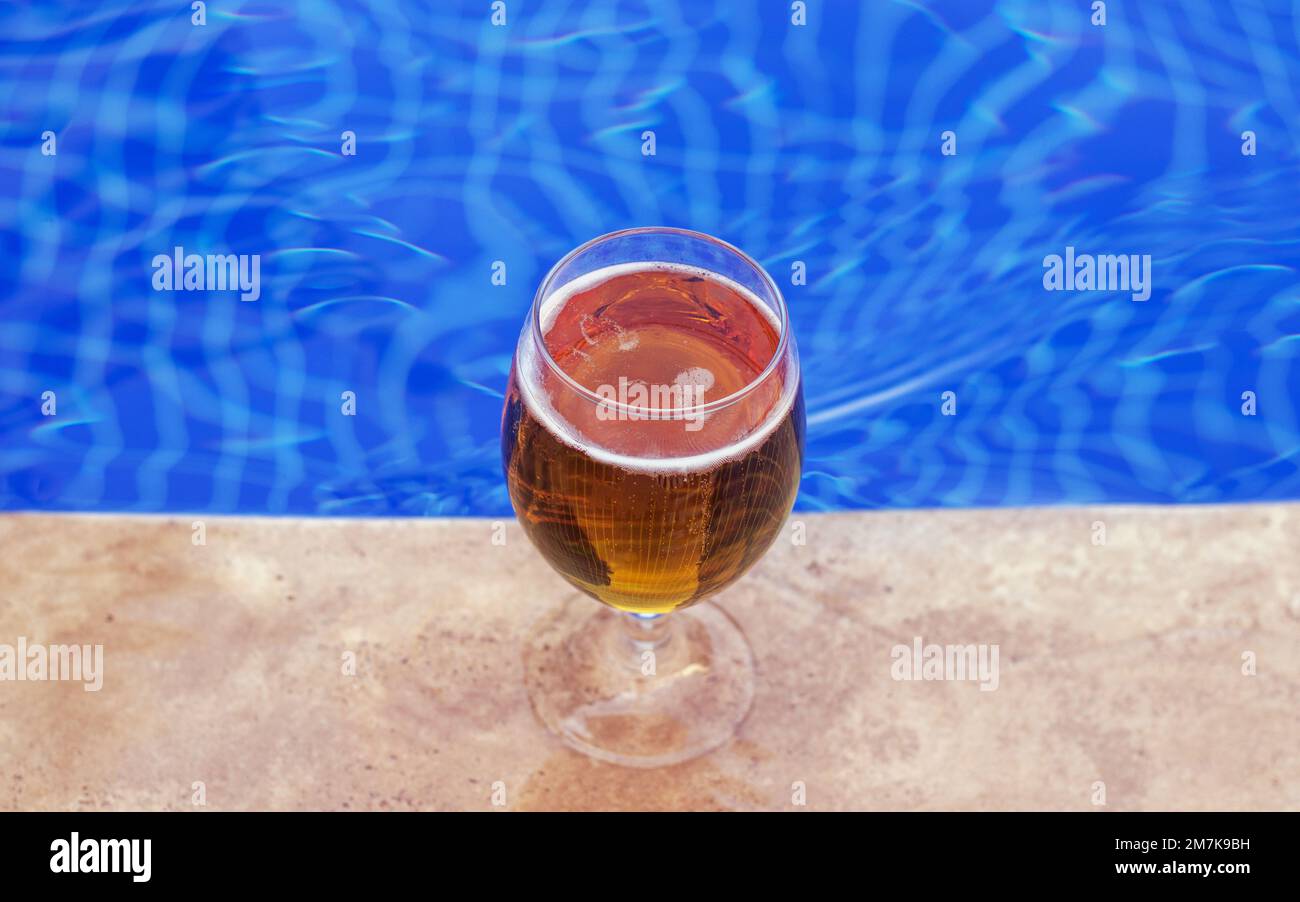 glass with fresh cold beer on pool edge blue color water waves mockup