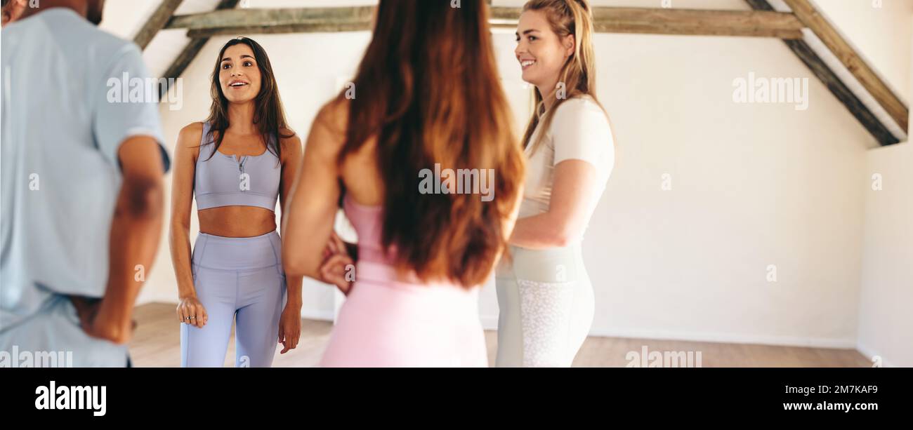 Panoramic view of a group of sporty people talking to each other while standing in a circle. Group of happy friends sharing mental wellness tips durin Stock Photo
