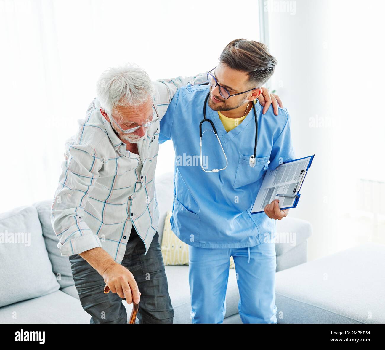 nurse doctor senior care caregiver help assistence retirement home nursing helping holding hug elderly man woman health support walking cane stick Stock Photo
