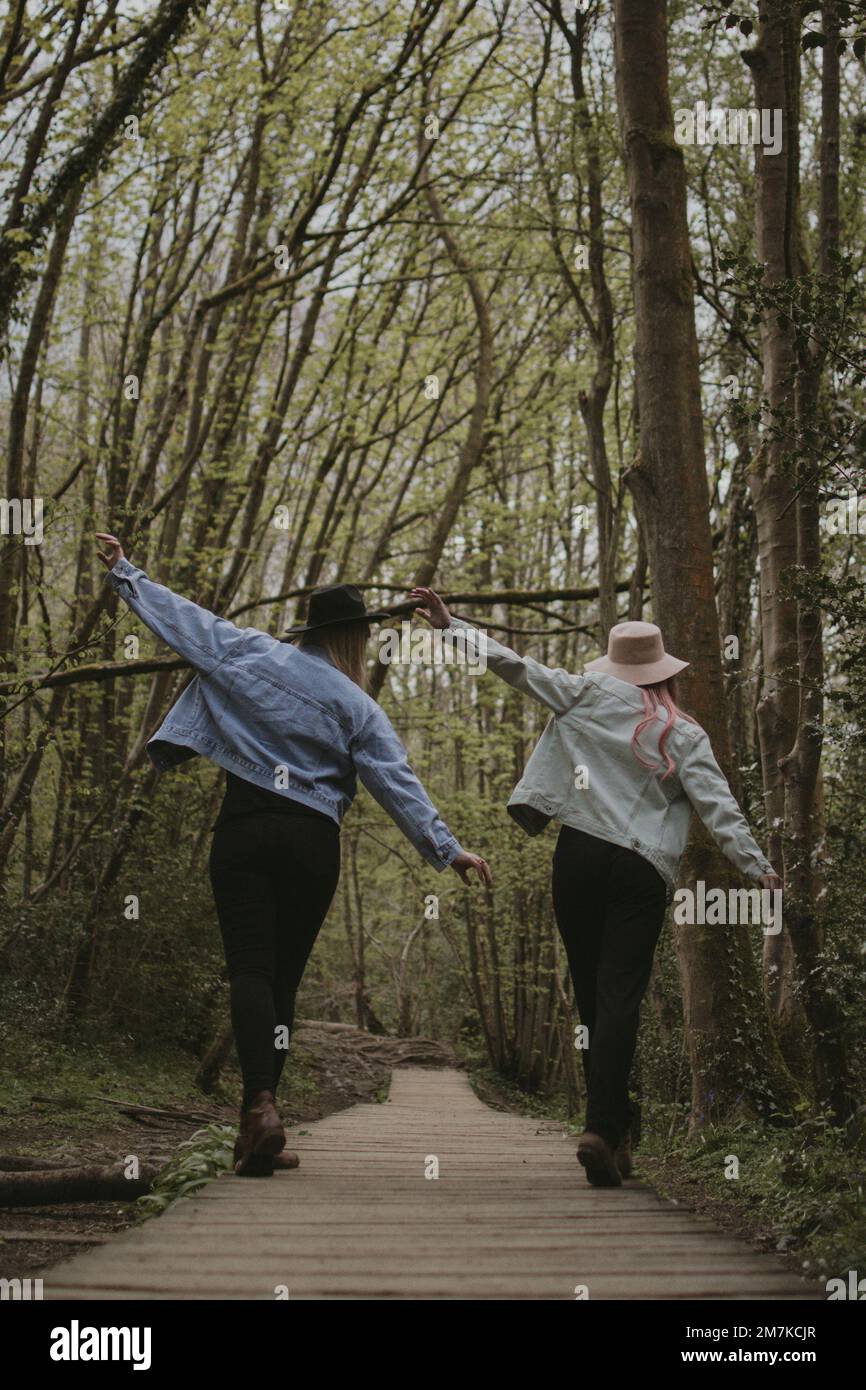 A vertical shot of happy couple wearing rancher hats walking between