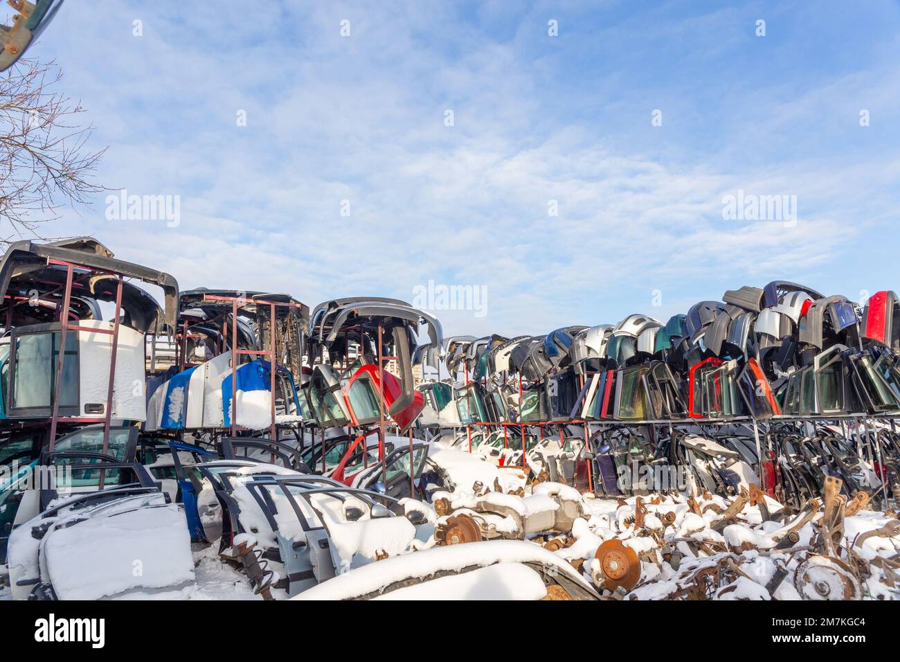 Disassembled cars on a car dump are on sale for spare parts. A stack of car suspensions, doors and bumpers. Trade in used spare parts is a common busi Stock Photo