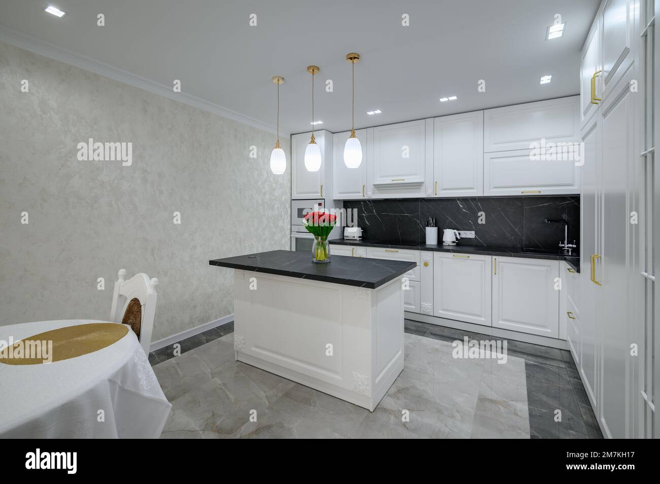 White modern domestic kitchen with island and black marble worktop ...