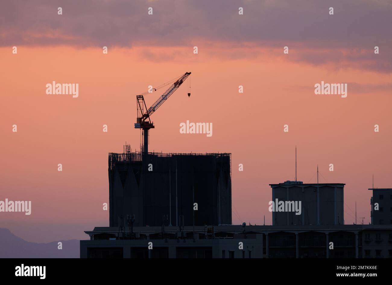 Rooftop crane atop low rise building after sunset Stock Photo - Alamy