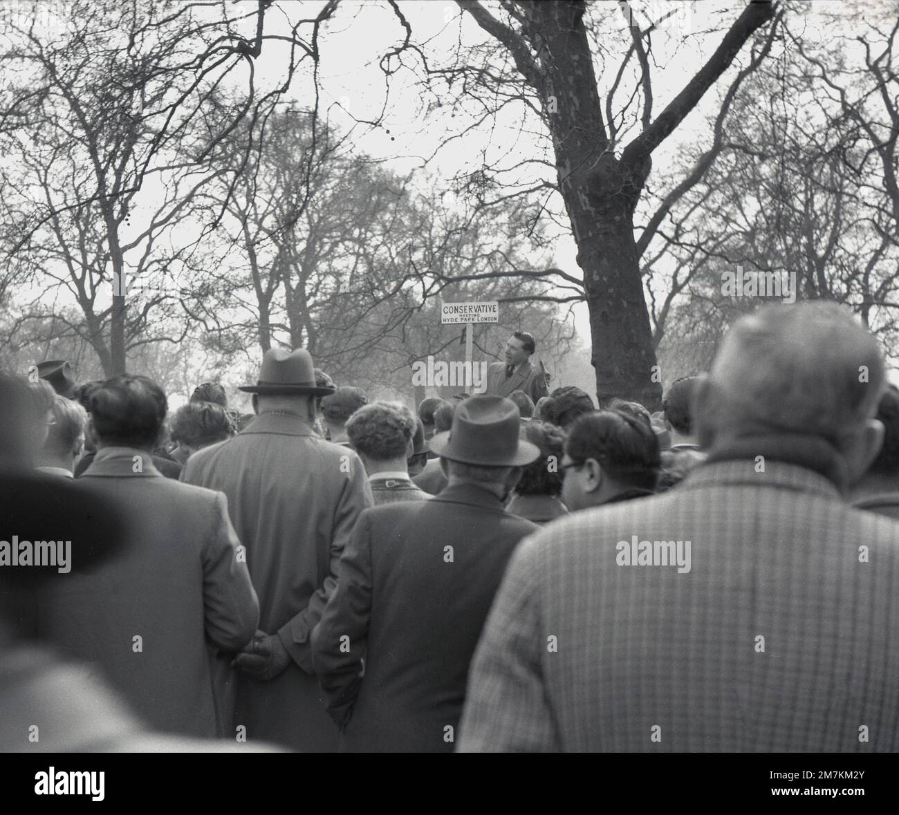 1950s, historical, people in London's Hyde Park at speakers corner, a public speaking platform, listening to a man holding a placard saying Conservative Meeting. Since the mid-1800s, an area in the Royal Park has been a place for a Sunday soapbox for people to communicate to the masses, including notable figures such as George Orwell and Karl Marx. Stock Photo