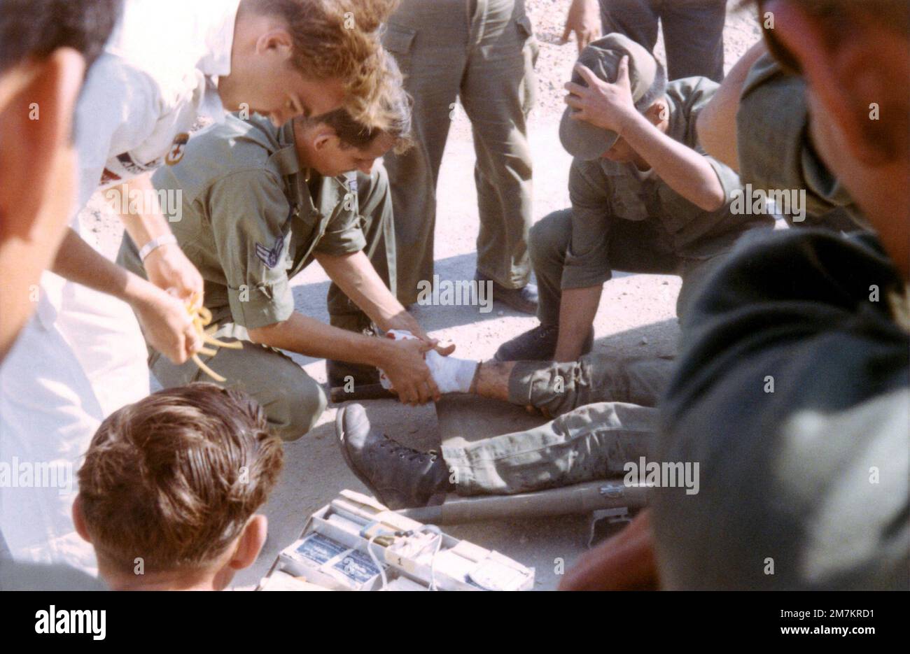 DF-SD-03-17790. [Complete] Scene Caption: Medics treat the blown of foot of an Army of the Republic of Vietnam (ARVN) soldier immediately after he was extracted from a burning minefield at Bien-Hoa Air Base in the Republic of Vietnam (RVM). The soldier lost a foot when he stepped on a landmine. Nobody could figure out how to extract the wounded soldier without tripping the mines. AIRMAN First Class (A1C) William Hart Pitsenbarger, Pararescue Crew Member, Detachment 6, 38th Aerospace Rescue and Recovery Squadron (ARRS) said, 'No problem, just lower me down on the penetrator, Ill straddle the gu Stock Photo