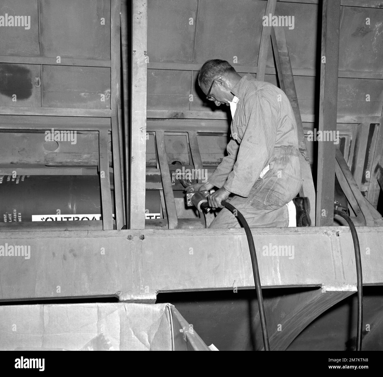 A man works to install a submarine emergency communication transmitter (SEC) buoy Mark 9 Mod O outside the pressure hull and inside the other hull of a simulated submarine hull section during testing at the Naval Ordnance Laboratory. When put into fleet use the SECT will be released and act as a surface marker if and when the ship is sunk. Base: White Oak State: Maryland (MD) Country: United States Of America (USA) Stock Photo