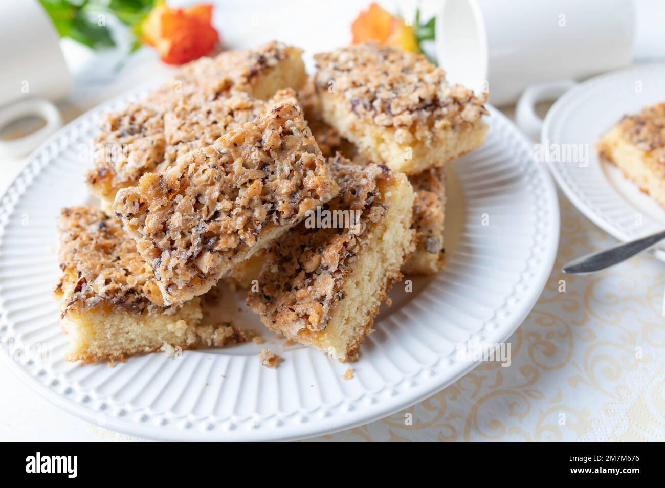 Plate with slices of hazelnut cake on white background Stock Photo