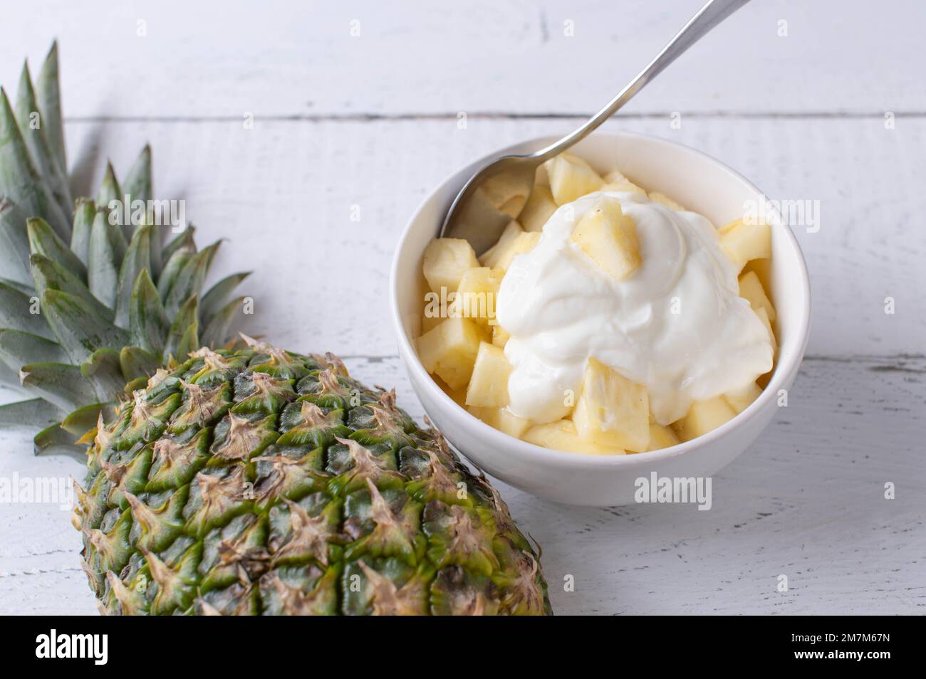 Post or pre workout meal or snack with chopped pineapple and high protein islandic skyr on white background with space for text Stock Photo