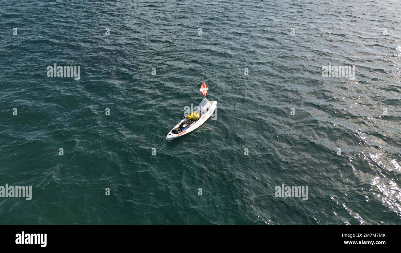 Aerial view looking down from above at a dive kayak with a dive flag