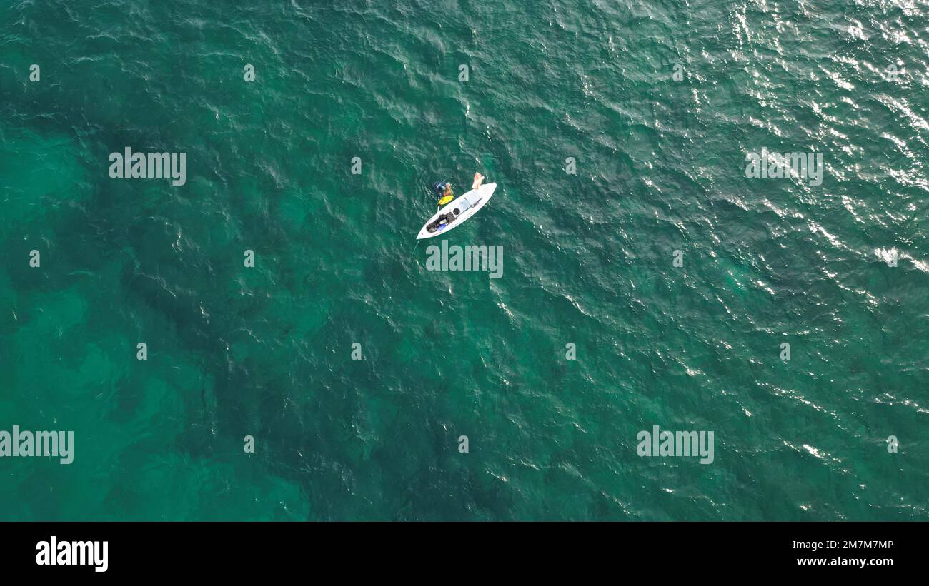 Aerial view looking down from above at a dive kayak with a dive flag