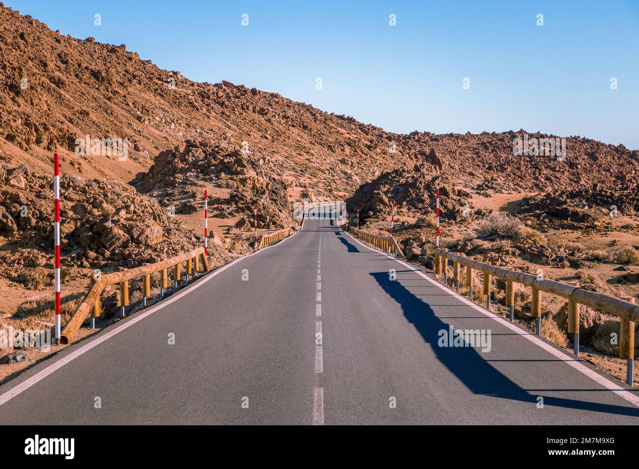 A straight asphalt road that curves in the distance, surrounded by ...