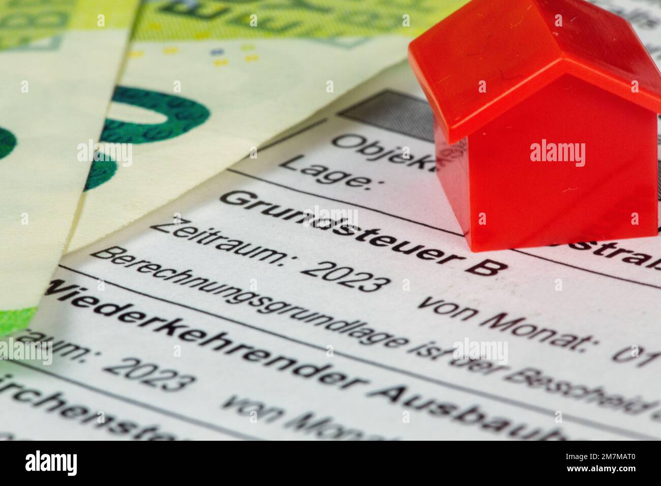 Nahaufnahme eines Bescheides über Grundbesitzabgaben mit Eurobanknoten und einem Modellhaus (Symbolbild) Stock Photo