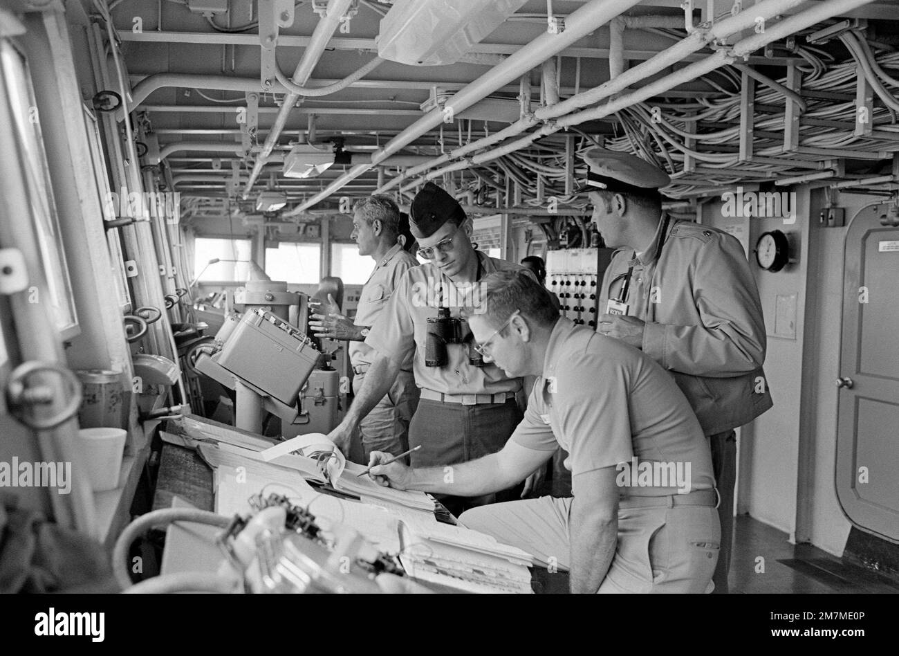 Rear Admiral Frederick F. Palmer, rear, Commander Amphibious Group Two, talks to crewman on the bridge of the amphibious command ship USS MOUNT WHINTEY (LCC 20) while en route to participate in the allied Exercise TEAM WORK '76. The MOUNT WHITNEY is serving as flagship during the exercise scheduled for September 15-24. Subject Operation/Series: TEAM WORK '76 Country: Unknown Stock Photo