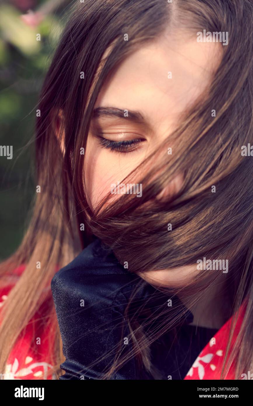 Young girl covers her face with a strand of hair Stock Photo