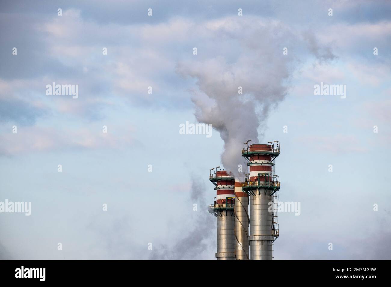 Smokestack exhaling smoke in a refinery with the sky in the background Stock Photo